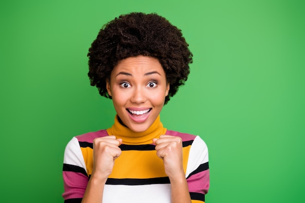 Portrait of amazed cheerful afro american girl hear want expect hope success victory achievement news impressed raise fists scream wear trendy clothes 