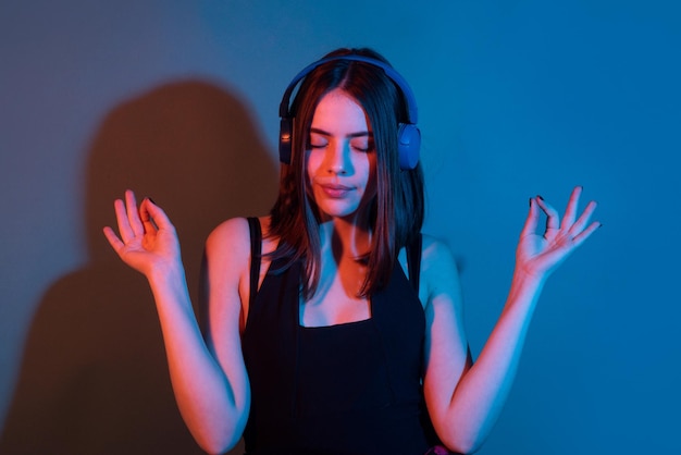 スタジオの背景に隔離されたヘッドフォンで音楽を聴いている驚いた踊る女の子の肖像画