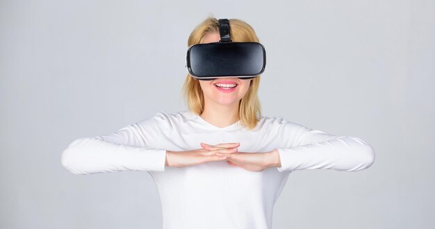 Ritratto di una ragazza stupita che utilizza un auricolare per realtà virtuale isolato su sfondo grigio woman