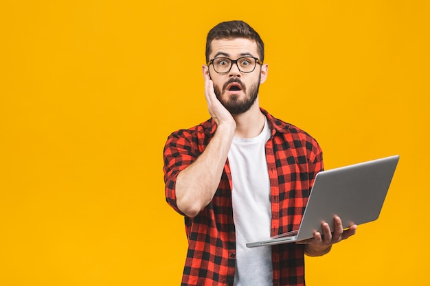 Portrait of amazed man holding laptop computer