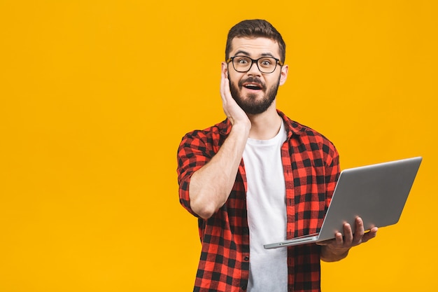 Portrait of amazed man holding laptop computer