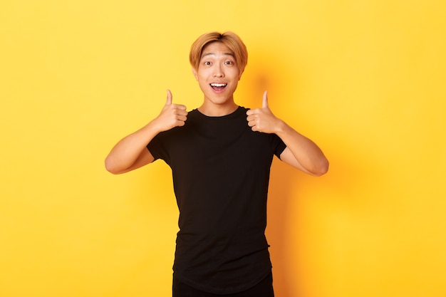 Portrait of amazed and pleased asian guy in black outfit