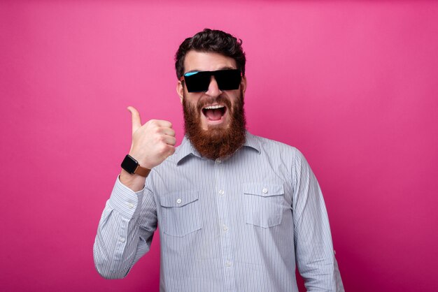 Portrait of amazed screaming man showing thumbs up