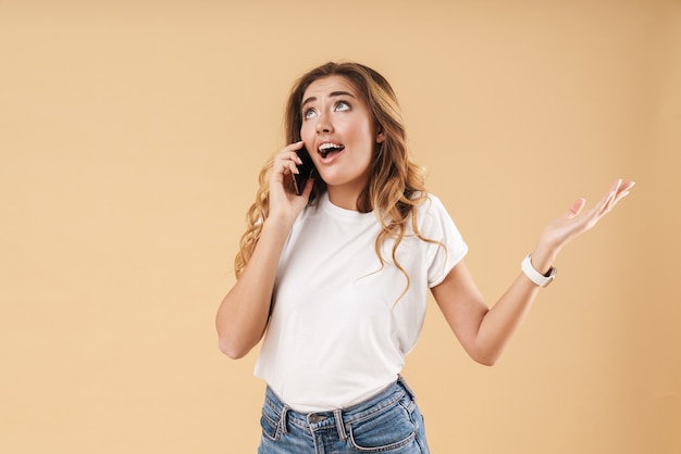 Portrait of amazed woman expressing surprise while talking on cellphone isolated