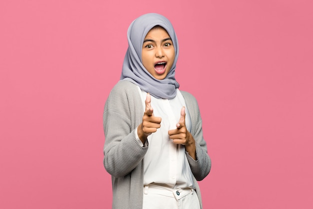 Photo portrait of amazed young asian woman pointing fingers to camera with open mouth