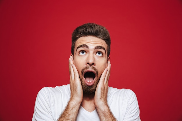 Photo portrait of an amazed young bearded man screaming loud