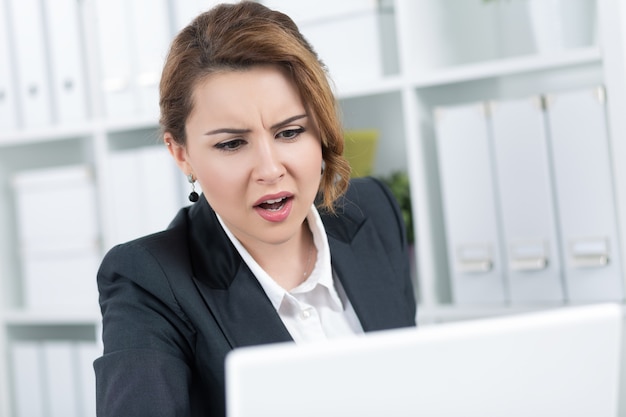 Portrait of amazed young business woman looking intently at laptop monitor