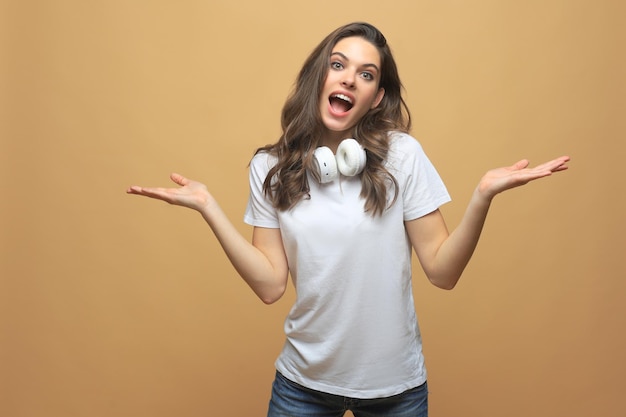 Portrait of amazed young woman over beige background.