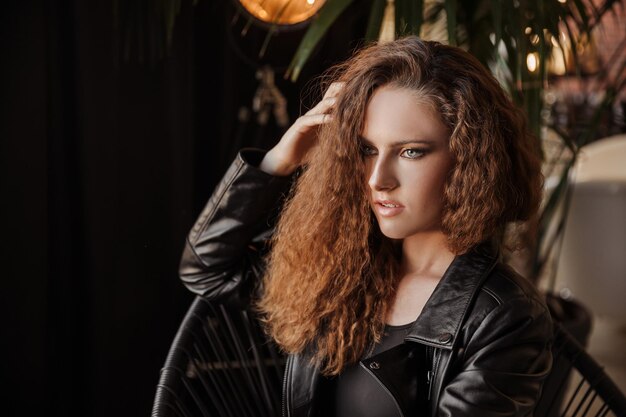 Portrait of a amazing red haired curly girl in a black leather jacket