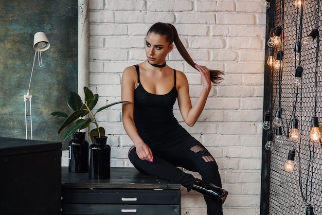 Portrait of amazing stylish young woman, posing at loft style room. Stunning long legs, perfect and attractive figure.