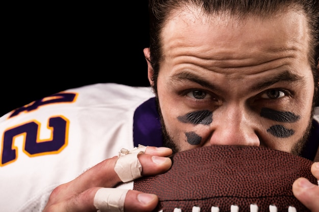 Portrait of american football player holding a ball and looking