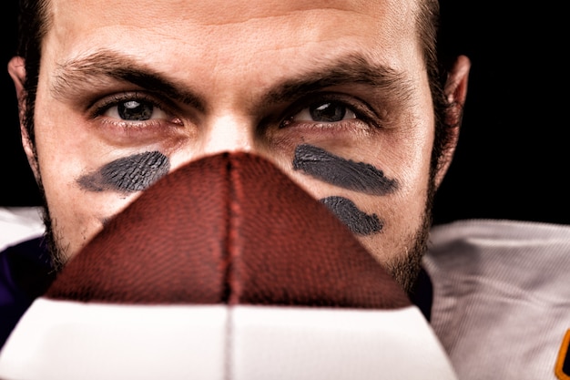 Portrait of american football player holding a ball and looking