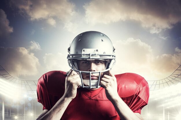 Portrait of American football player holding helmet against rugby stadium