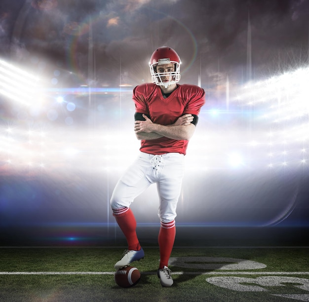 Portrait of american football player with arms crossed against american football arena