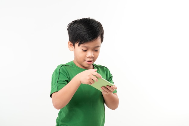 Portrait of an amused cute little kid playing games on smartphone isolated over white