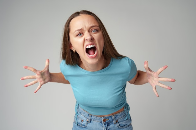 Photo portrait of angry crazy young woman on gray background