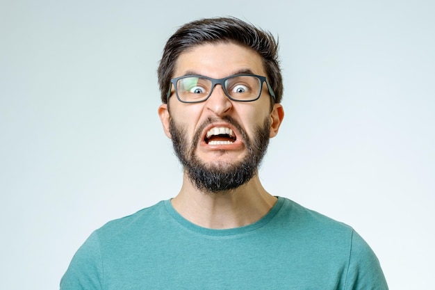 Portrait of an angry and furious male on a gray background The image is depicting emotions of anger and frustration