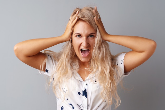 Portrait of angry irritated young woman over gray background 