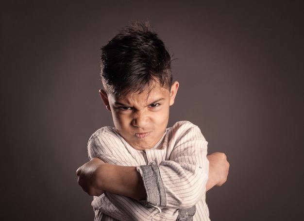 Portrait of angry kid on gray