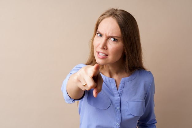Portrait of angry outraged young woman pointing at camera