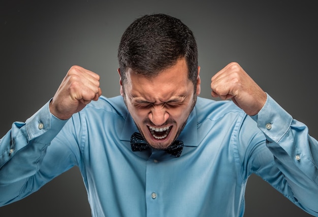 Portrait angry upset young man in blue shirt butterfly tie