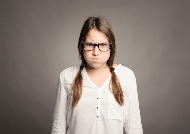 Portrait of angry young girl on gray background