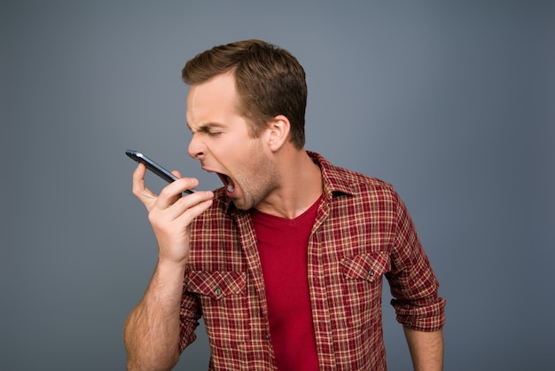 Portrait of angry young man screaming on his mobile phone