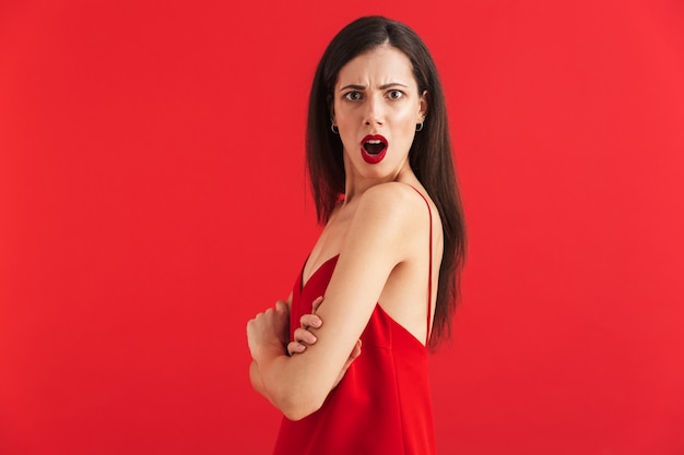 Portrait of an angry young woman in dress isolated, holding hands folded