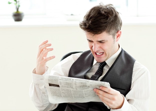 Photo portrait of a annoyed businessman reading a newspaper