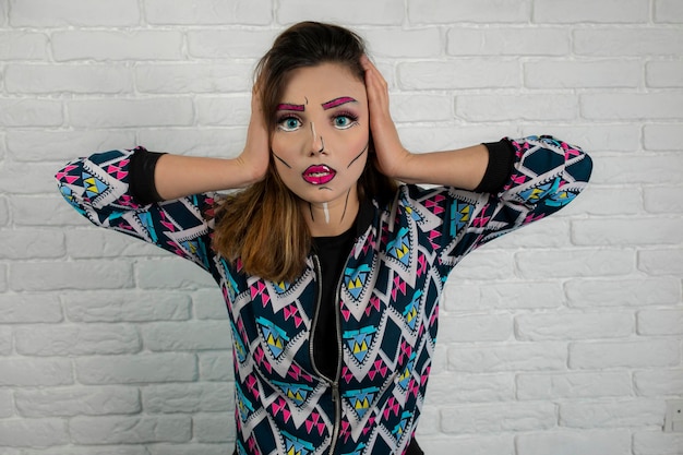 Portrait of an annoyed girl wearing creative makeup and put hands to her head. High quality photo