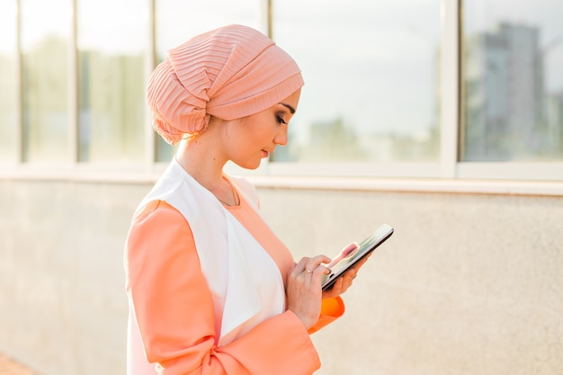 Portrait of Arab businesswoman holding a tablet. The woman is dressed in an abaya.