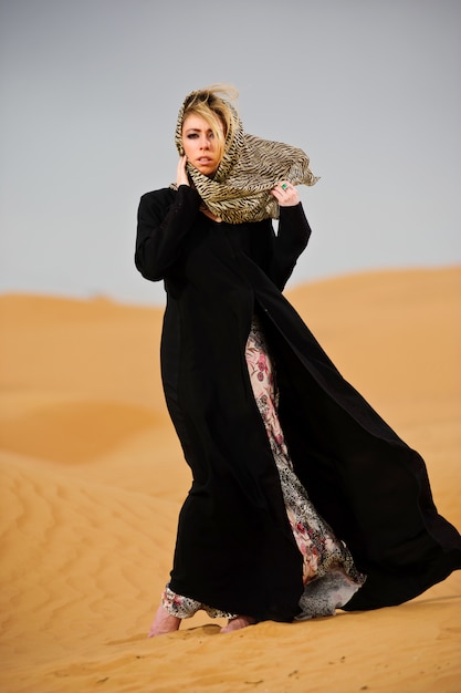 Portrait of arabic way dressed woman in yellow desert