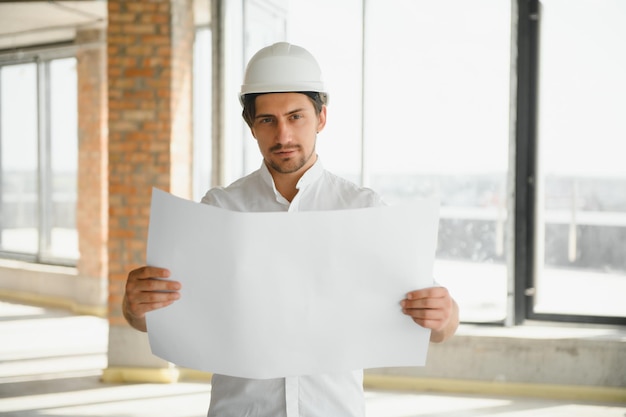 Portrait of an architect builder studying layout plan of the rooms serious civil engineer working with documents on construction site building and home renovation professional foreman at work