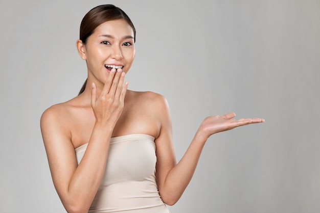 Portrait of ardent woman looking at camera holding empty space for advertising