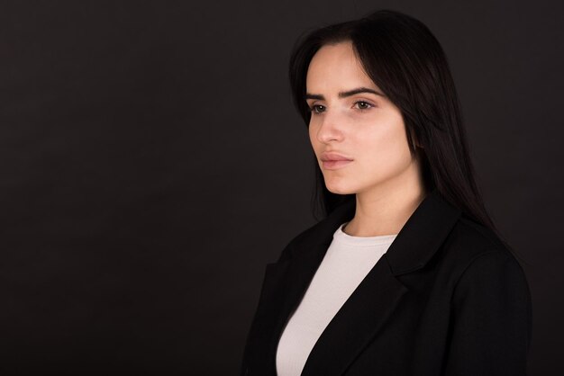 Portrait of an armenian brunette girl in a black jacket on a\
black background