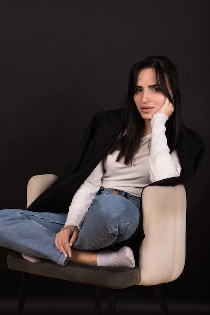 Portrait of an armenian brunette girl in a black jacket on a\
black background