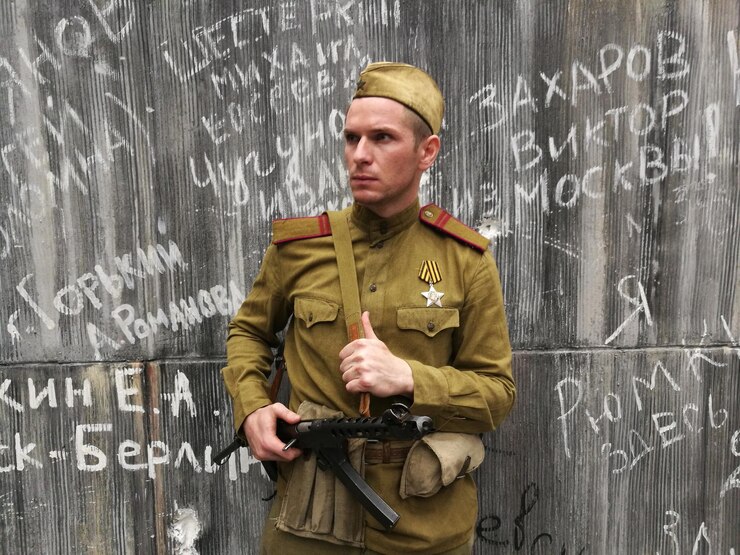Фотография портрет солдата армии с пистолетом, стоящего на стене с граффити