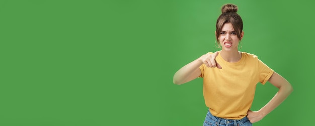 Photo portrait of arrogant impolite young woman in yellow tshirt pointing at camera squinting and