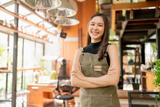 Portrait of asian adult female woman wear apron standing at entrance of her workshop pottery studio incasual cloth relax smiling confident and warm welcomeasian woman with her home studio workshop