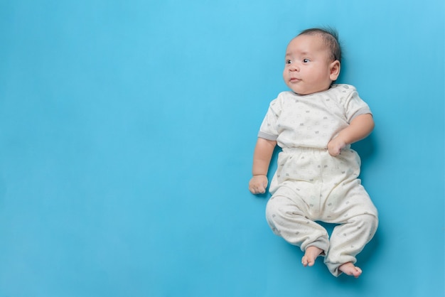 Ritratto del neonato asiatico che si trova sull'azzurro con uno spazio della copia