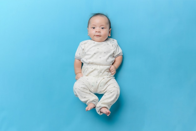 Portrait of Asian baby boy lying on light blue with a copy space