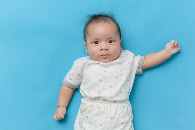 Portrait of Asian baby boy lying on light blue with a copy space