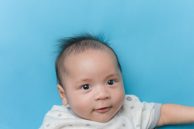 コピースペースで水色に横たわっているアジアの男の子の肖像画