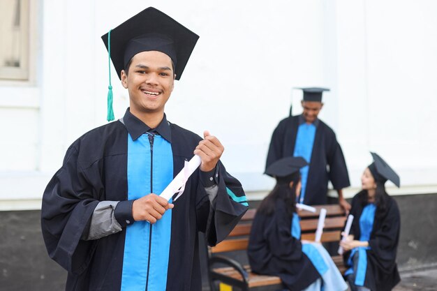 Portrait of Asian bachelor man smiling at camera and showing okay sign near blurred friends in unive