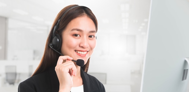 Ritratto di bello operatore sorridente sorridente del telefono del servizio clienti della donna in ufficio backgr