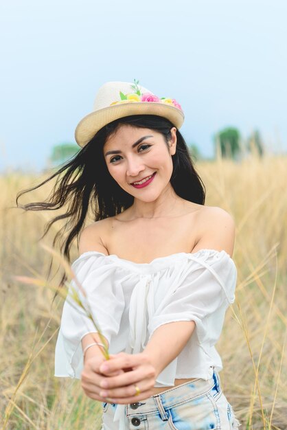 Portrait of asian beautiful woman feeling fresh hat in her hand at the fieldwear denim with brown boot