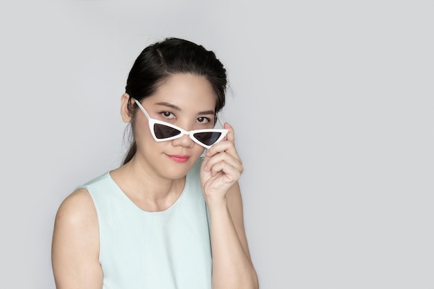 Portrait of Asian beautiful woman peeking over sunglasses with inquisition