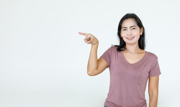 Ritratto asiatico bella donna che indossa camicia casual in piedi pose, indicando la pubblicità su sfondo bianco, copia spazio vuoto con uno sguardo sorridente isolato alla telecamera.