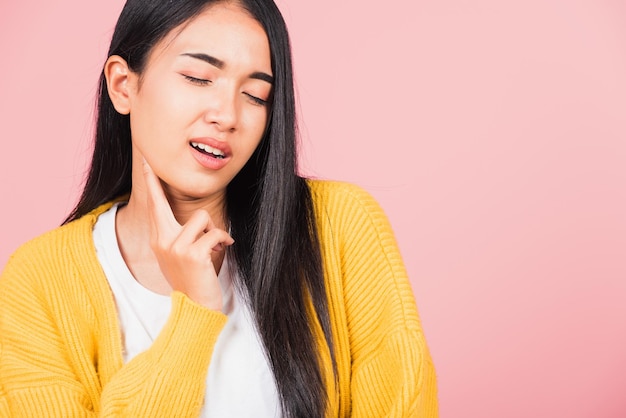 Portrait of Asian beautiful young woman has chin pain, female painful use finger touching itching his chin, studio shot isolated on pink background, Health and medical problem and Dental care concept