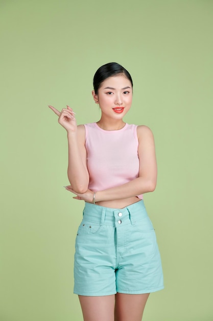 Portrait of Asian beautiful young woman pointing one hand with finger on side with smile face